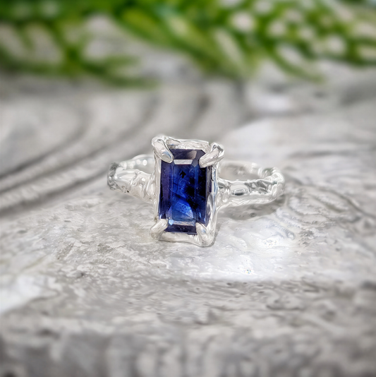 Blue sapphire engagement ring in solid sterling silver with textured band, showcasing a unique emerald-shaped design.