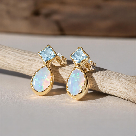 Gold earrings with opal and Aquamarine gemstones on a wooden background