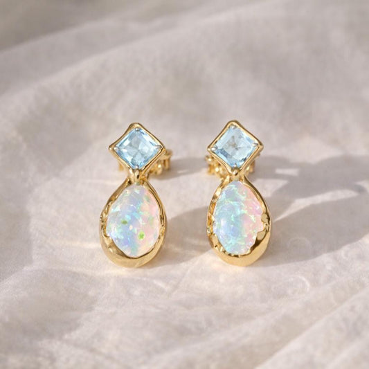 Pair of gold stud earrings with opal and Aquamarine on a light background