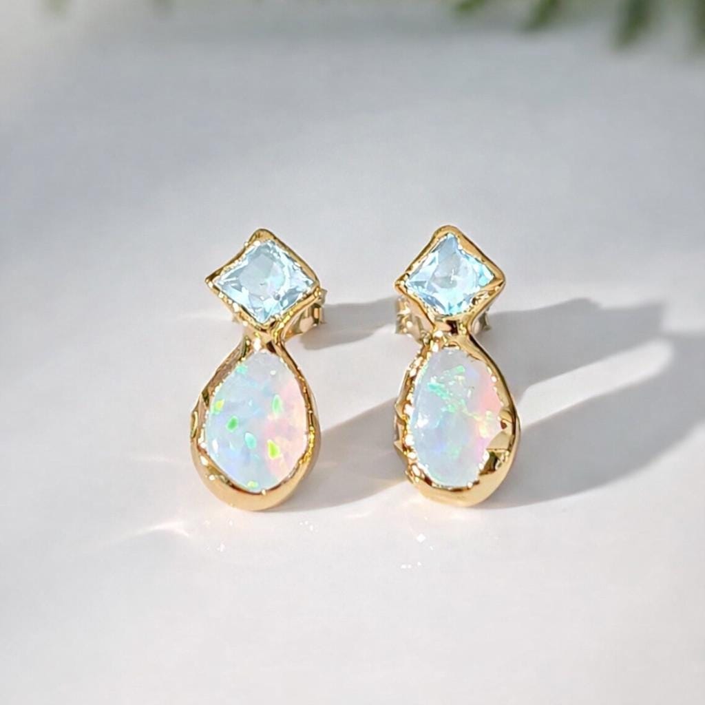 Gold earrings with Aquamarine and opal stones on a light background