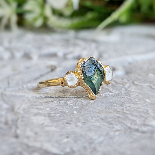 Unique raw green Sapphire and Herkimer diamond engagement ring on a textured surface, designed in 14k gold.