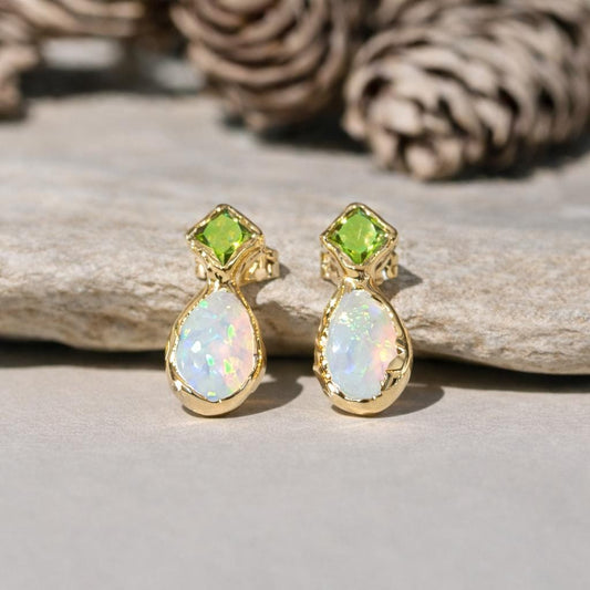 Gold earrings with opal and peridot stones on a wooden surface