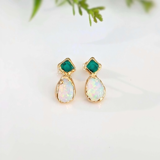 Pair of gold earrings with Emerald and opal stones on a light background