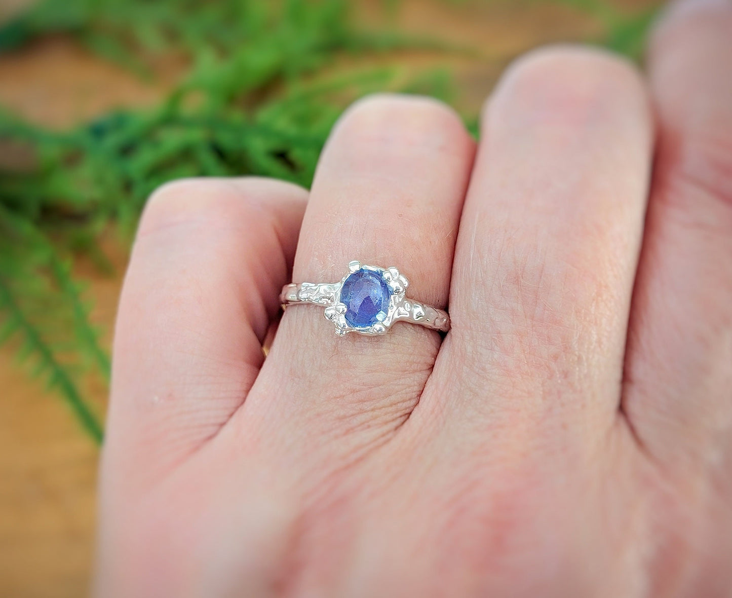 Handcrafted silver Tanzanite ring on a hand, featuring a purple gem and textured band, symbolizing elegant individuality.