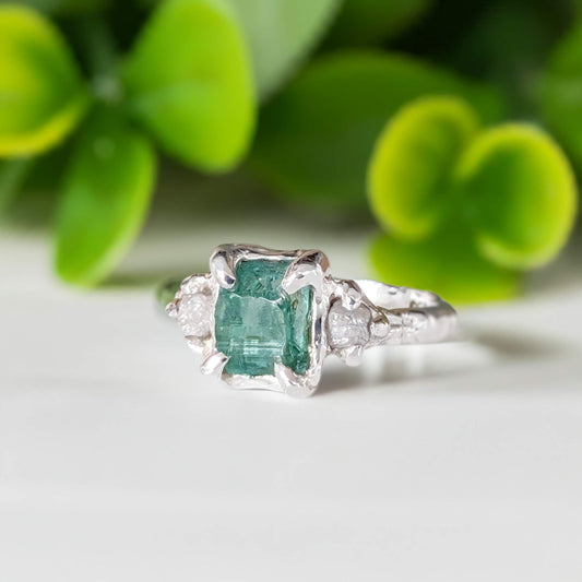 Raw emerald and diamond engagement ring in solid sterling silver, showcasing a mint green emerald and two raw diamonds.