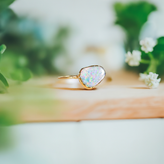 Handcrafted Australian Opal ring on a 14k gold filled band, surrounded by greenery for a stunning presentation.