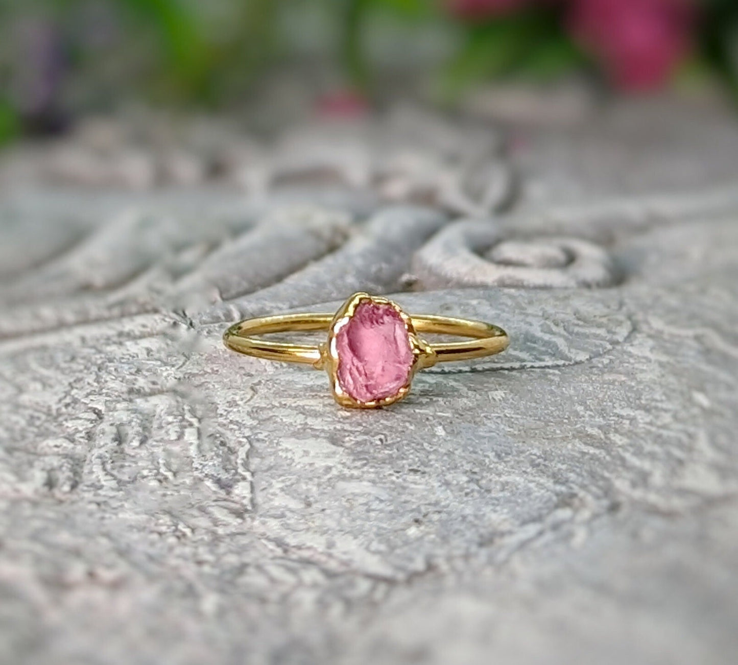 Raw pink spinel ring on a stone surface, featuring a natural crystal and a gold band, perfect for everyday wear.