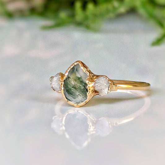 Moss Agate and raw diamond engagement ring on a gold band, showcasing a pear-shaped Moss Agate with raw Herkimer diamonds.