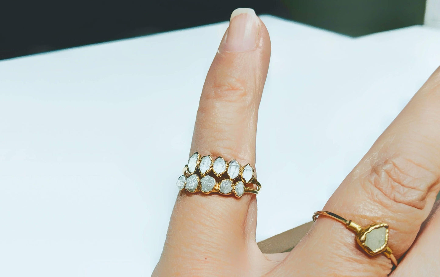 Handcrafted raw diamond eternity ring in 18k gold, showcasing unique sparkle on a woman's hand.