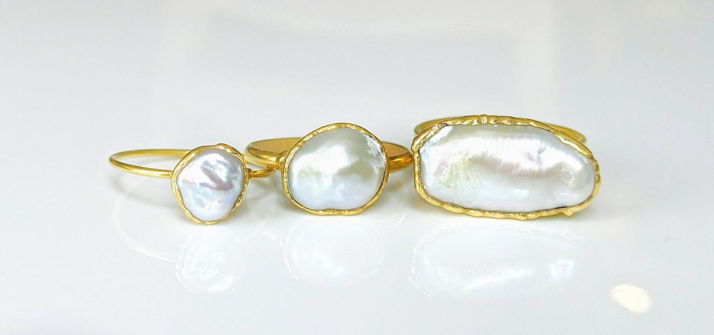 Three handmade Keshi pearl rings on gold bands showcasing unique shapes and luster.