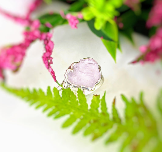 Raw pink Morganite ring on a bed of green ferns and colorful flowers, showcasing its unique electroformed design.