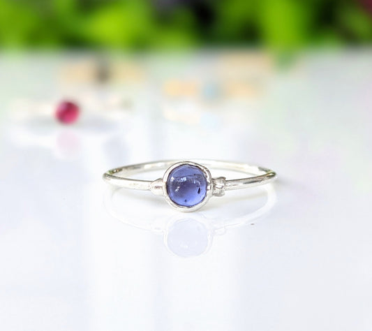 Dainty tanzanite stacking ring with natural purple-blue gemstone on a delicate sterling silver band.
