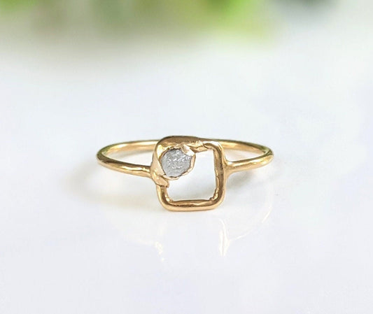 Minimalist solid gold ring featuring a unique raw diamond in a square setting.