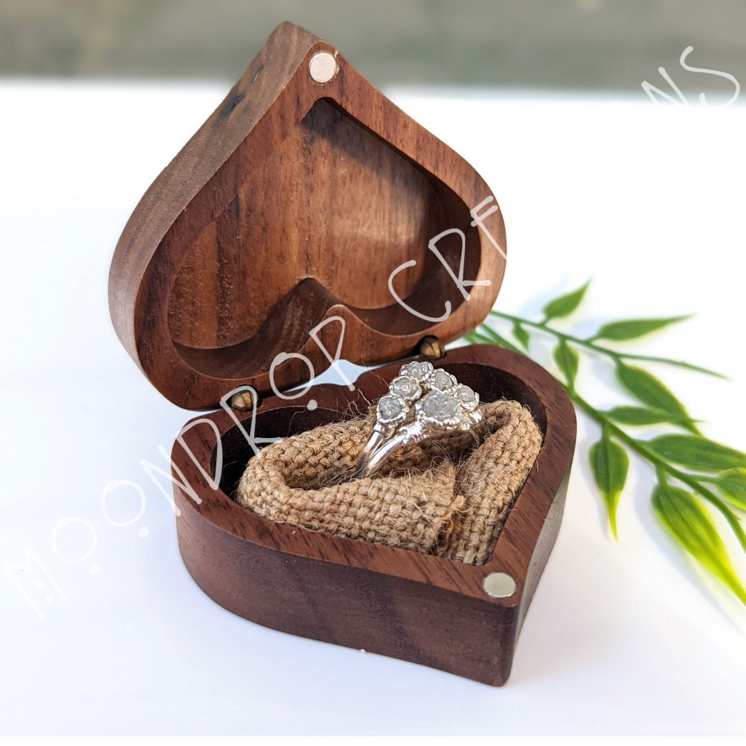 Heart-shaped wooden ring box showcasing a stunning wedding ring with a decorative design inside.