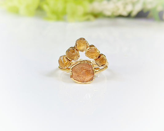 Raw Topaz and Citrine Chevron ring set on a glossy surface, featuring a golden band with five vibrant stones.