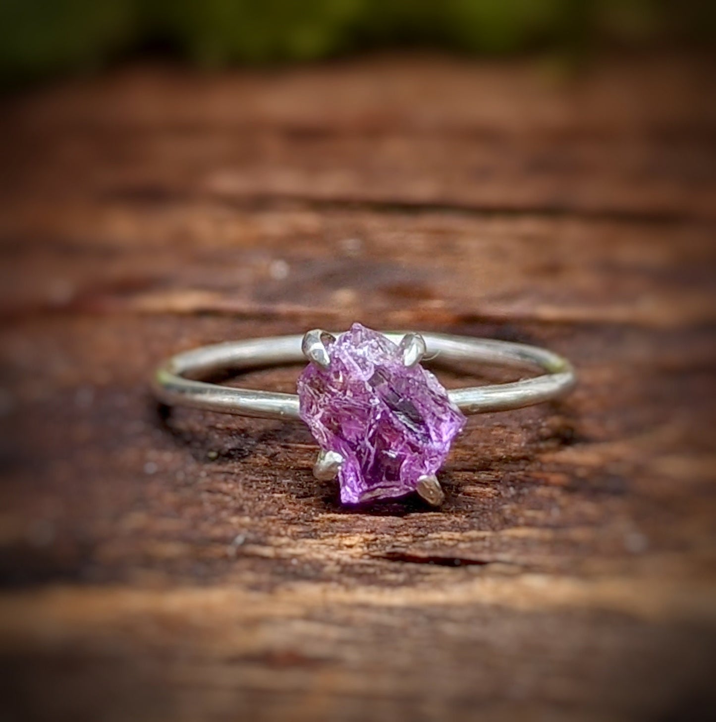 Raw Alexandrite ring in sterling silver on wooden surface, showcasing unique handcrafted design and vibrant colors.