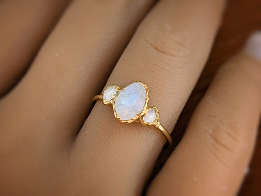Raw rainbow Moonstone and Herkimer diamond engagement ring on a hand with a delicate gold band.
