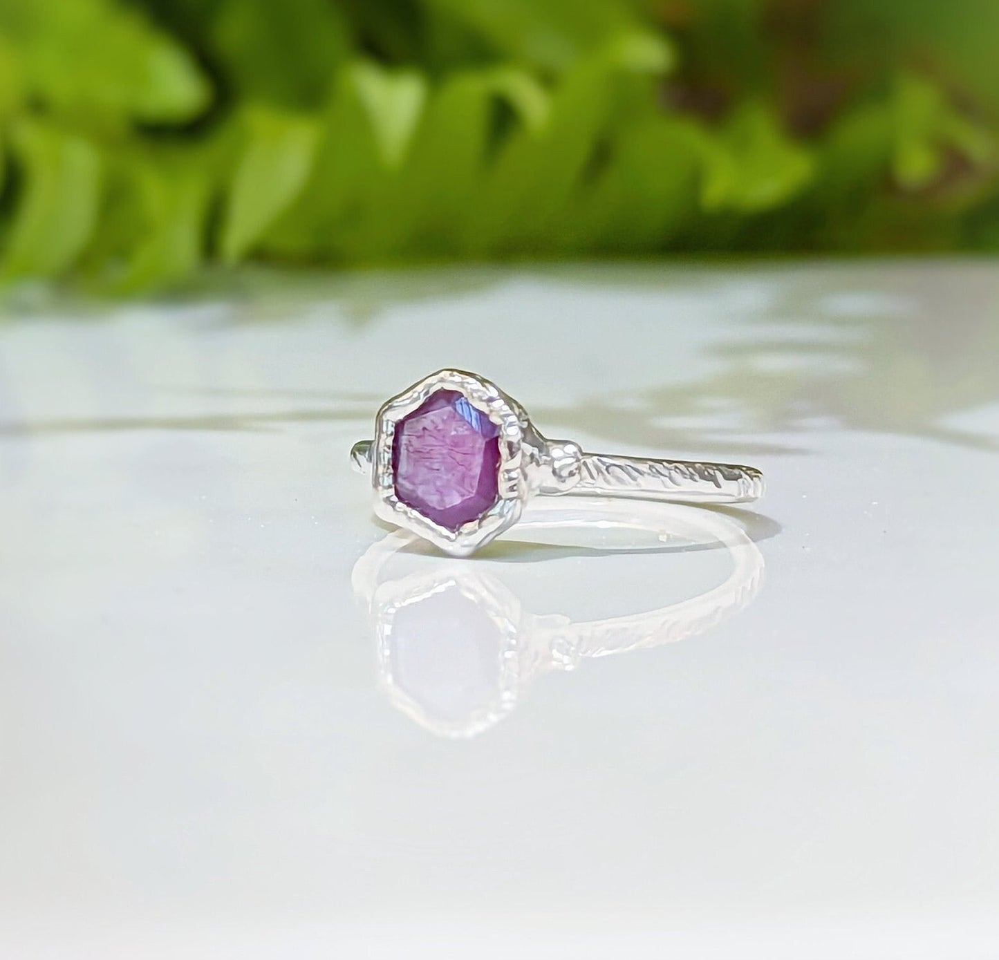 Elegant pink sapphire ring in silver settings reflecting natural beauty and unique craftsmanship.