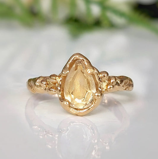 Handcrafted solid 14k gold citrine ring featuring a pear-shaped yellow crystal in a textured organic band.