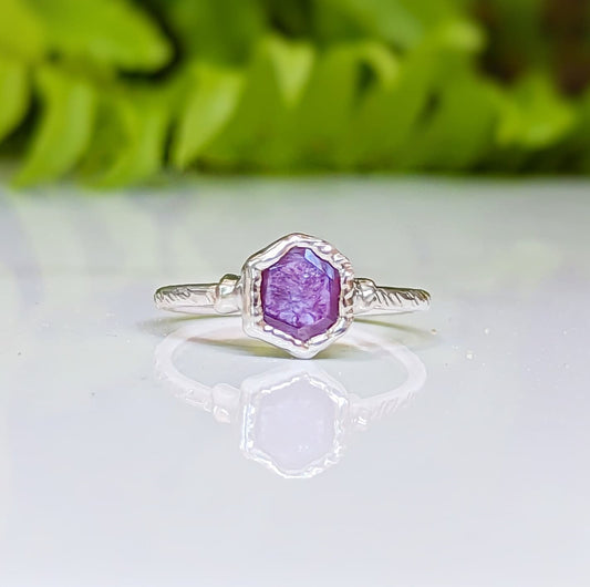 Handcrafted Pink Star Sapphire ring in Sterling Silver on reflective surface, showcasing unique hexagonal design.