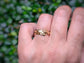 Handcrafted molten textured wedding band in Solid 14k Gold, worn on a hand with greenery background.
