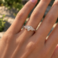A close-up of a person's hand wearing a diamond engagement ring.