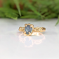 Raw Montana Sapphire engagement ring in solid 14k gold with an intricately textured band, showcasing unique elegance.