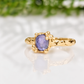 A gold ring with a large purple gemstone, likely a sapphire, set in a decorative gold band.