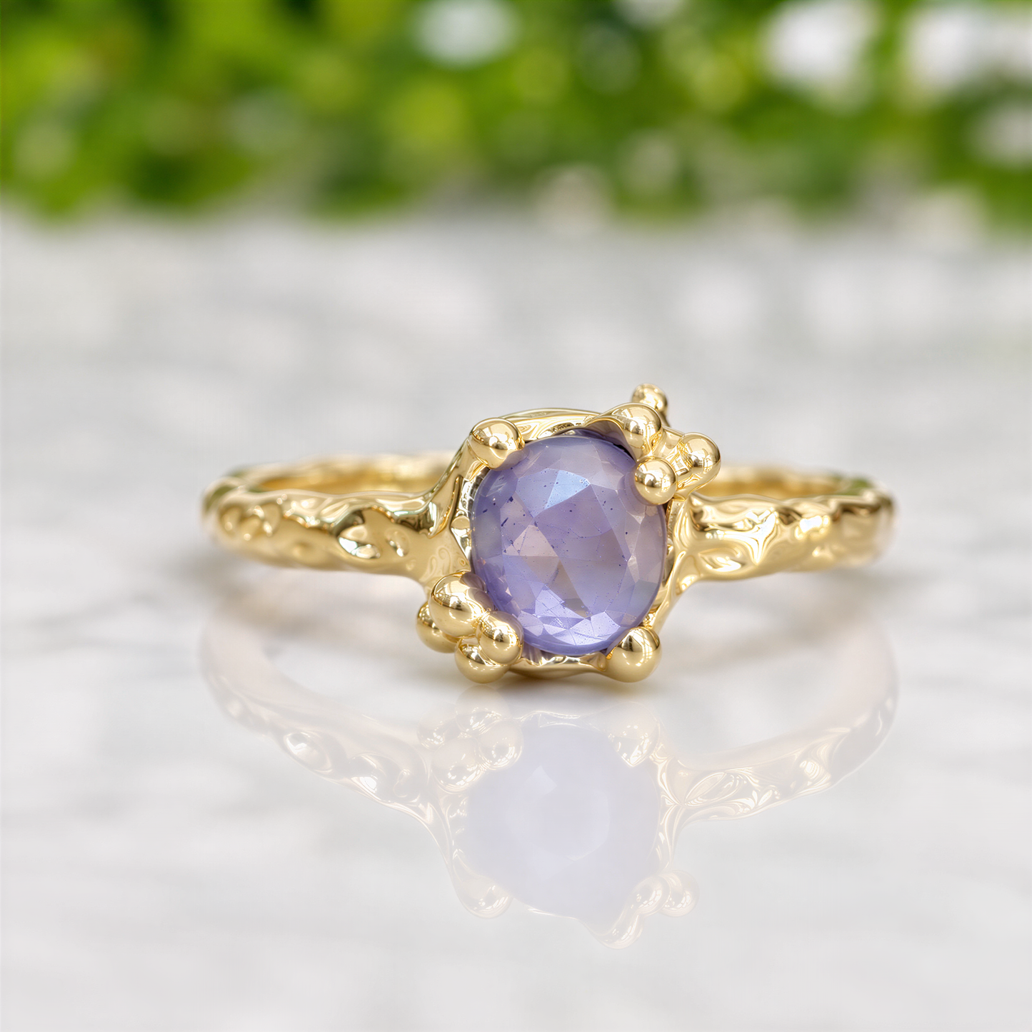 A gold ring with a large oval-shaped purple gemstone set in a decorative gold band.