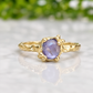 A gold ring with a large oval-shaped purple gemstone set in a decorative gold band.