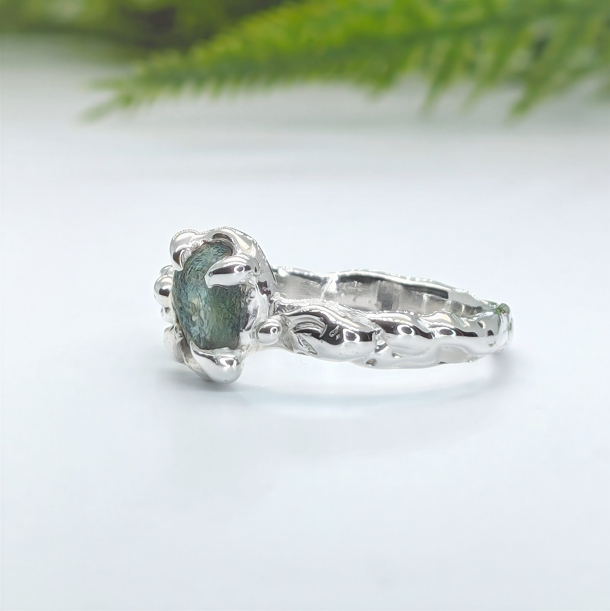 Handmade raw Montana Sapphire ring photographed outdoors with natural greenery