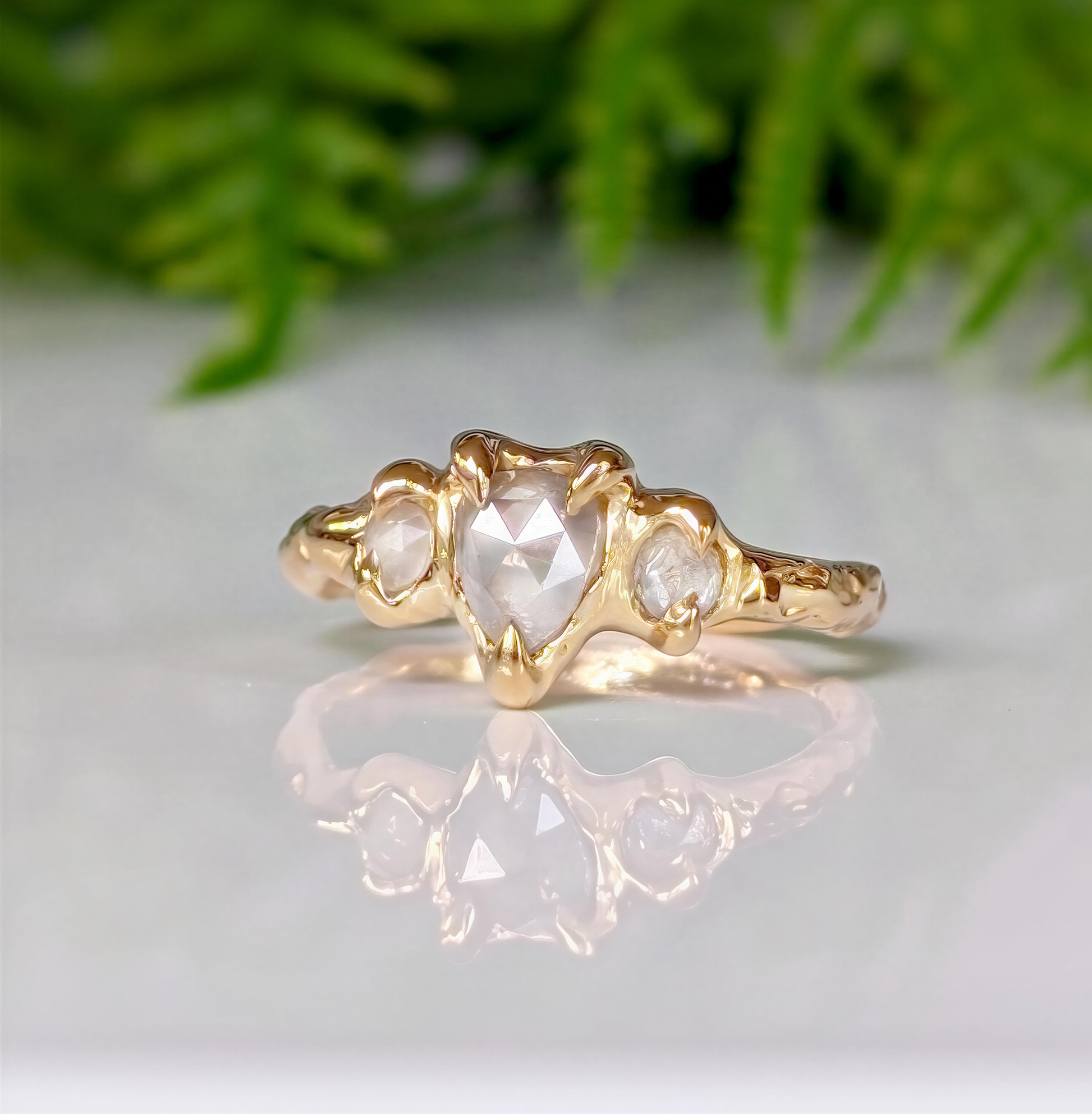 Rustic gold ring featuring a heart-shaped diamond and two side stones, ideal for unique engagement.