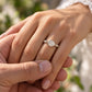 A close-up image of a person's hand wearing a diamond engagement ring.