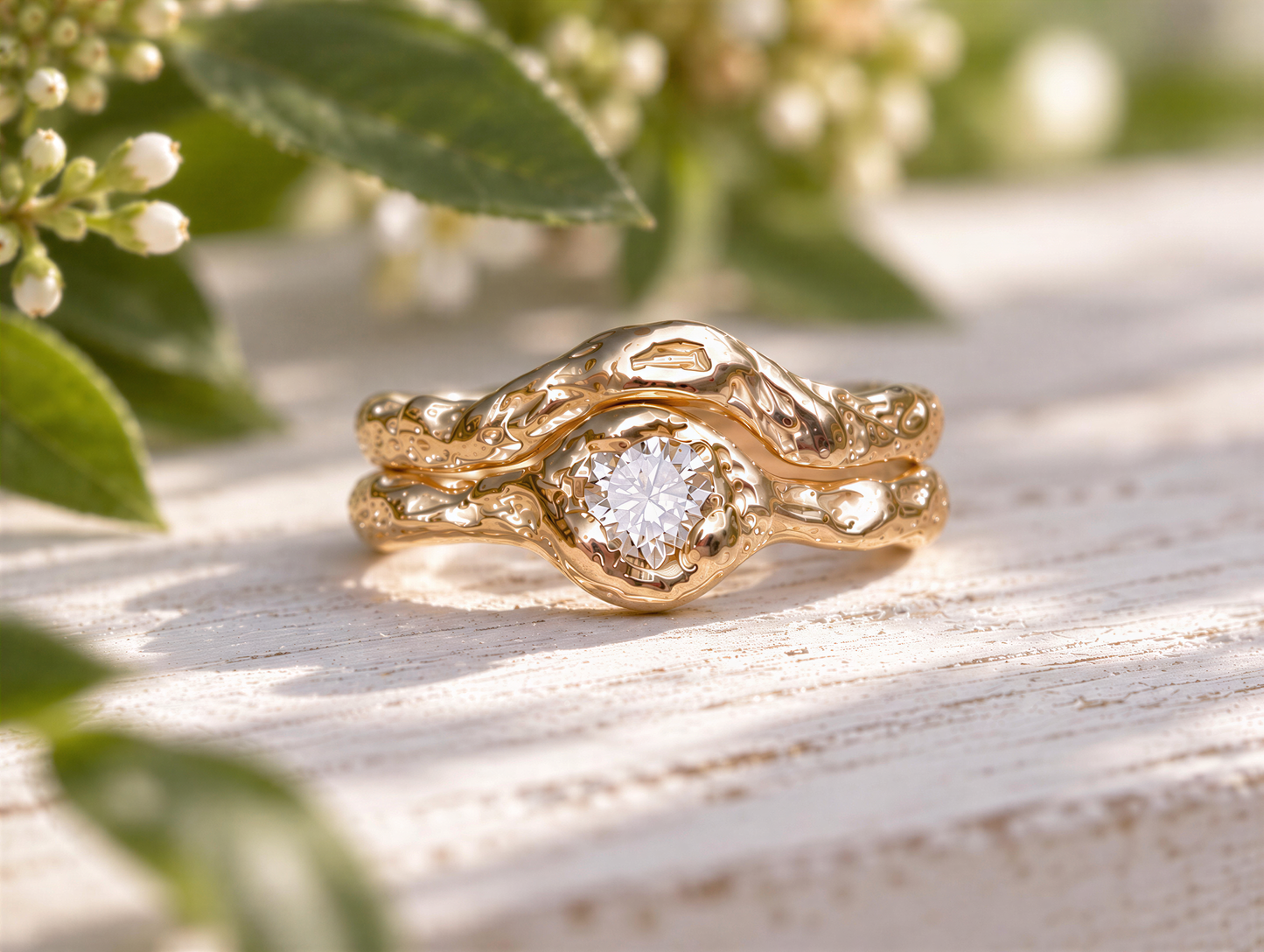 A gold ring with a large diamond set in the center, surrounded by a twisted, organic design, sits on a wooden surface with green leaves in the background.