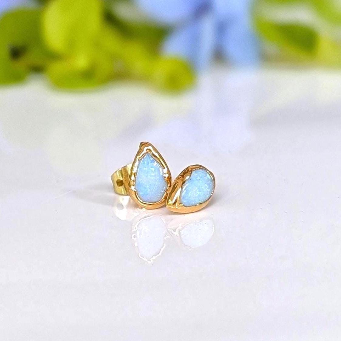 A pair of pear-shape white australian opal stud earrings in gold textured setting. The opals have lovely flashes of color.