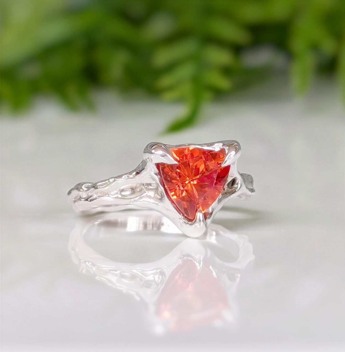 Handcrafted solid 14k gold ring featuring a radiant trilliant cut orange sapphire on a textured band.