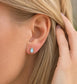 A woman wearing a pair of pear-shape white australian opal stud earrings in gold textured setting. The opals have lovely flashes of color.