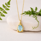 Gold necklace with an Aquamarine pendant on a white stone with greenery
