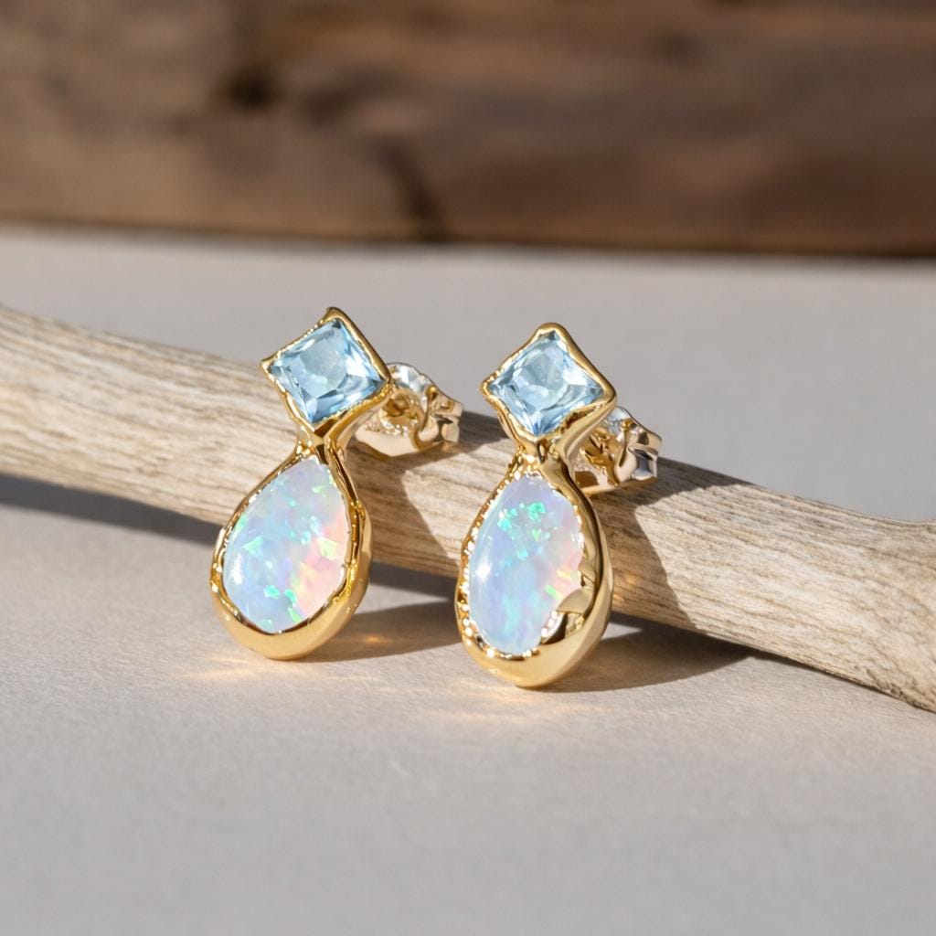 Gold earrings with opal and Aquamarine gemstones on a wooden background