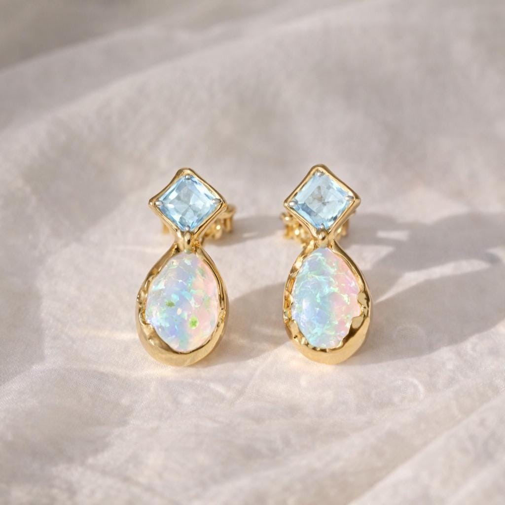 Pair of gold stud earrings with opal and Aquamarine on a light background