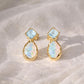Pair of gold stud earrings with opal and Aquamarine on a light background