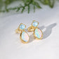 Gold earrings with blue and iridescent stones on a light background