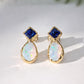 Pair of Gold stud earrings with blue Sapphire and Opal on a white background