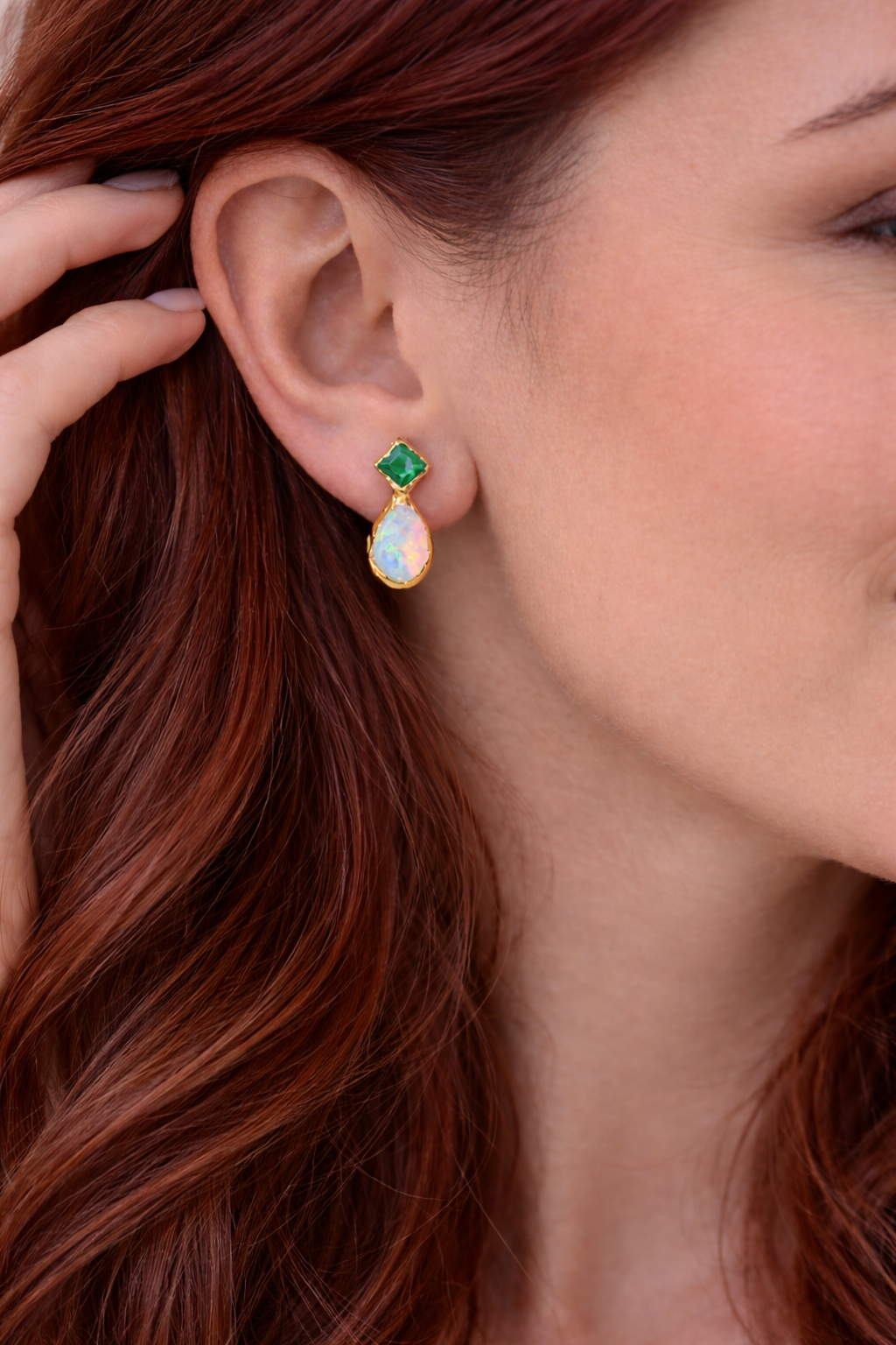 Woman wearing a pair of Emerald and Opal stud earrings