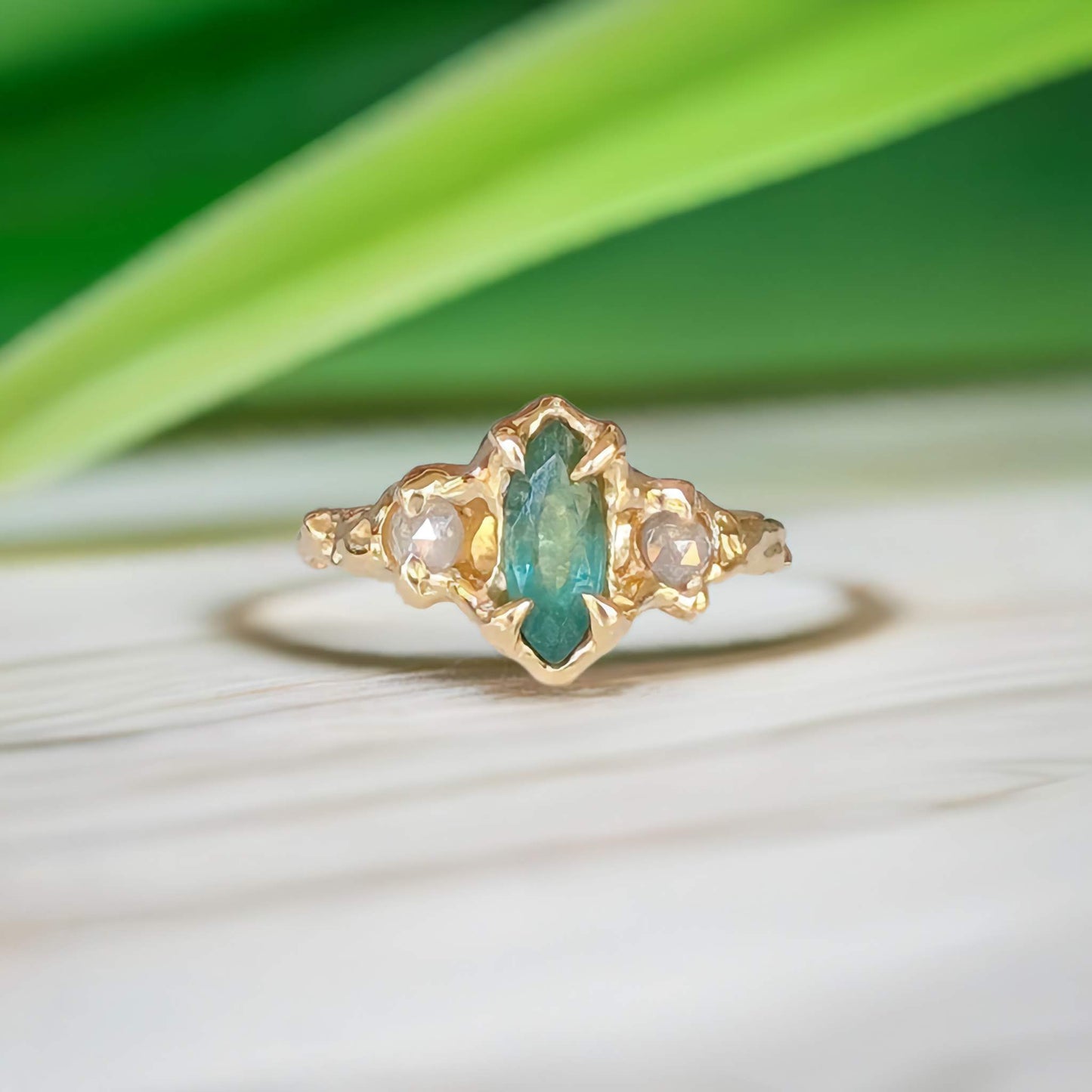 Emerald and diamond engagement ring in 14k gold, featuring marquise cut emerald and salt & pepper diamonds, nature-inspired design.