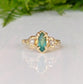 Emerald and diamond engagement ring in solid 14k gold, featuring a marquise cut emerald and salt & pepper diamonds.
