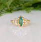 Emerald and diamond engagement ring in solid 14k gold, featuring a marquise cut emerald and salt & pepper diamonds.