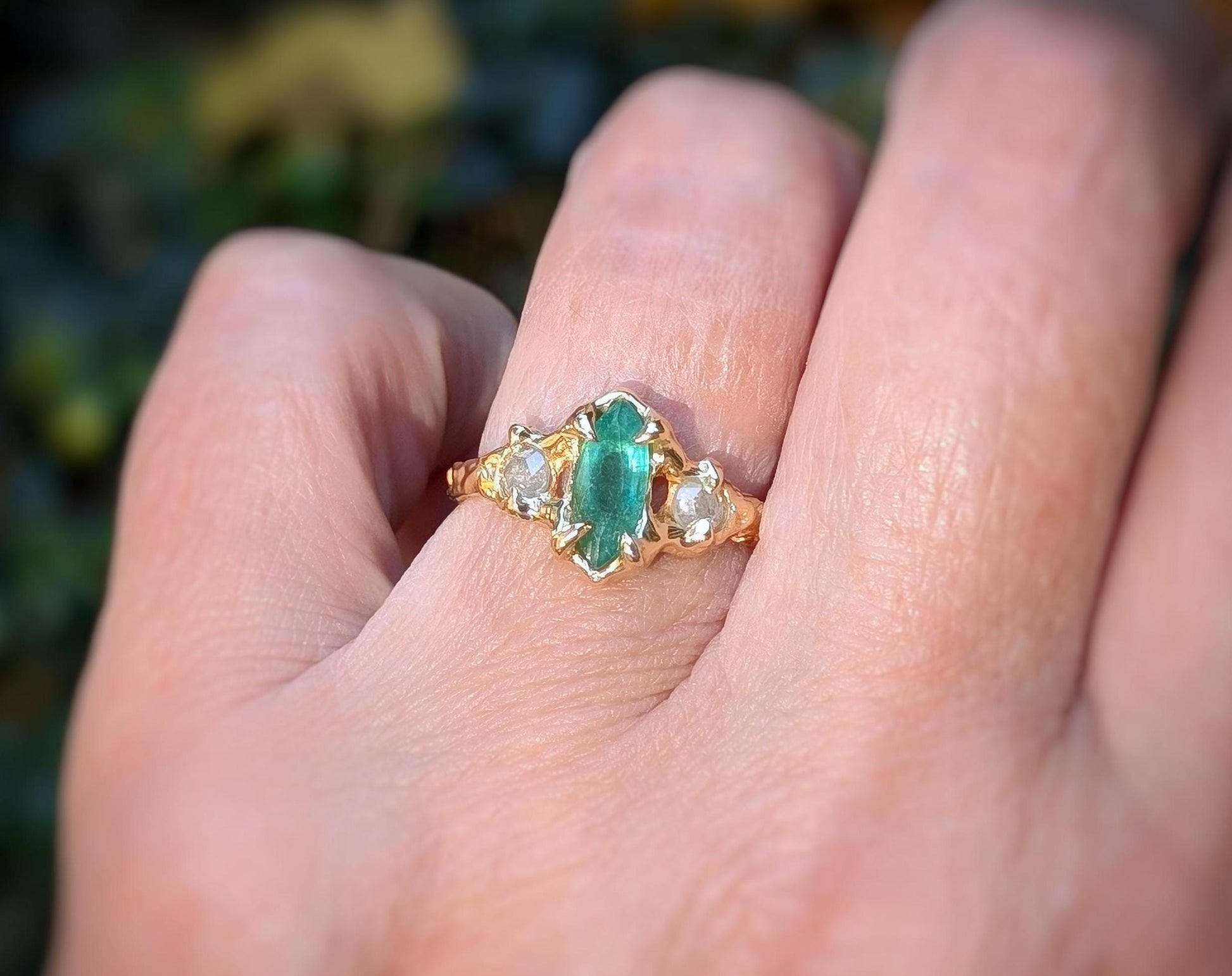Emerald and diamond engagement ring with marquise cut emerald and salt & pepper diamonds in 14k gold setting.