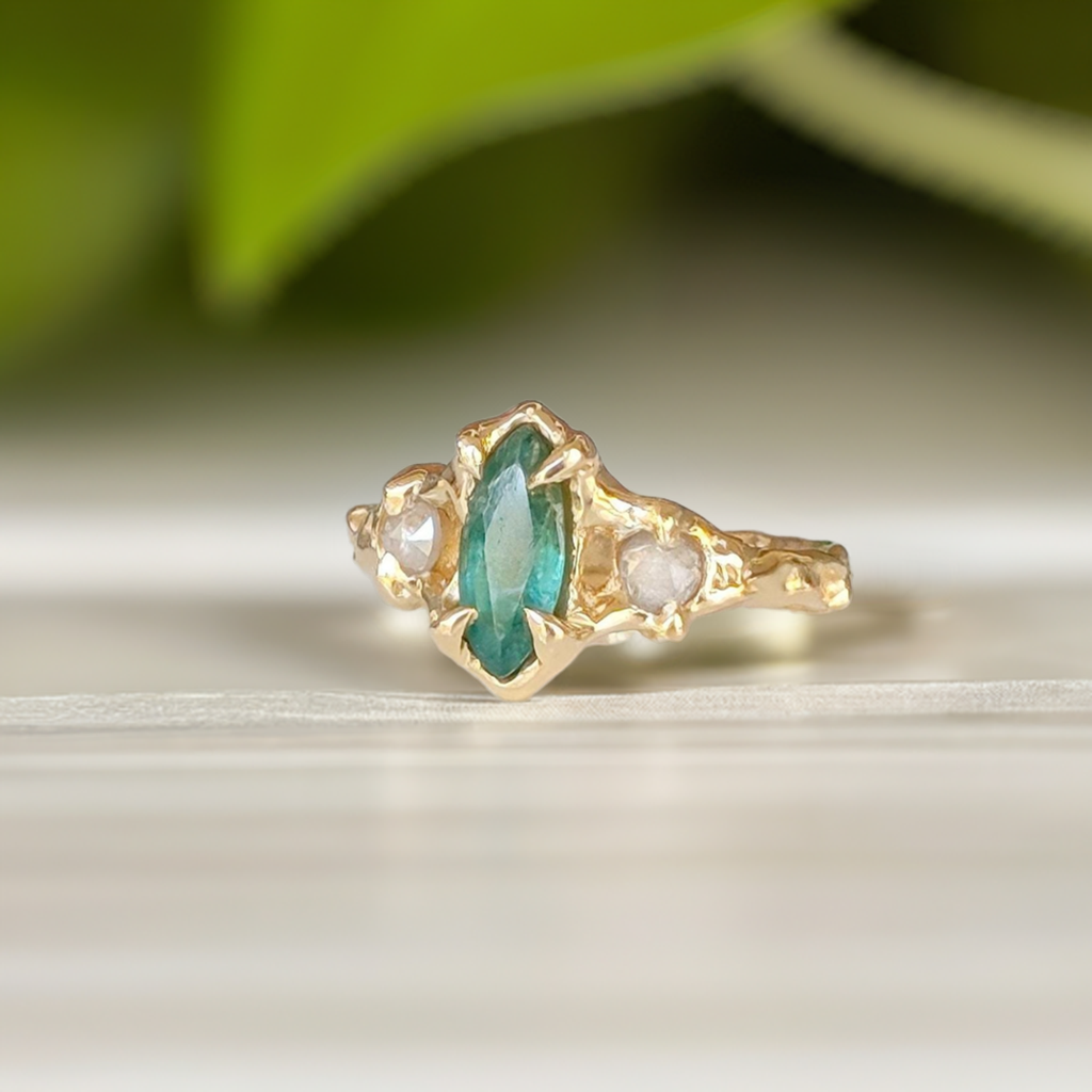 Emerald and diamond engagement ring in solid 14k gold with marquise cut emerald and salt & pepper diamonds.