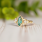 Emerald and diamond engagement ring in 14k gold featuring a marquise cut emerald and salt & pepper diamonds.